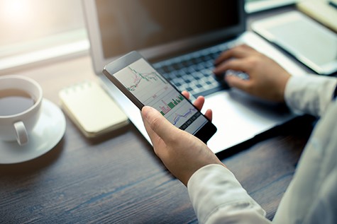 Hand holding smartphone with stock graph