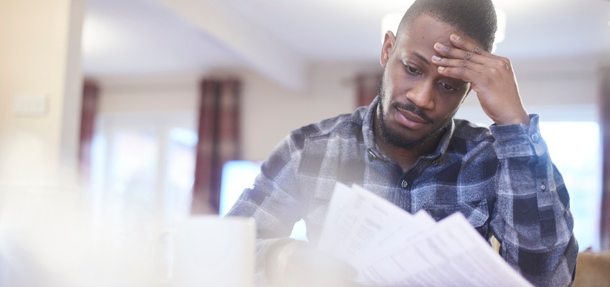 Worried young male reading household bills (©iStockphoto.com/919382170)