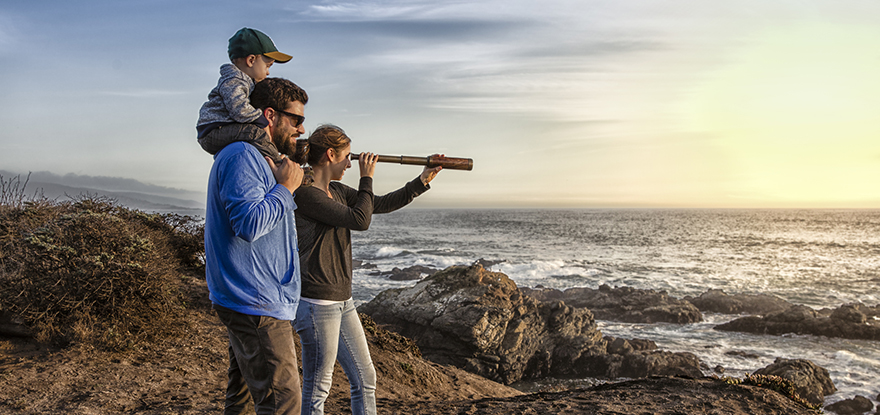 Family with spyglass looking toward ocean