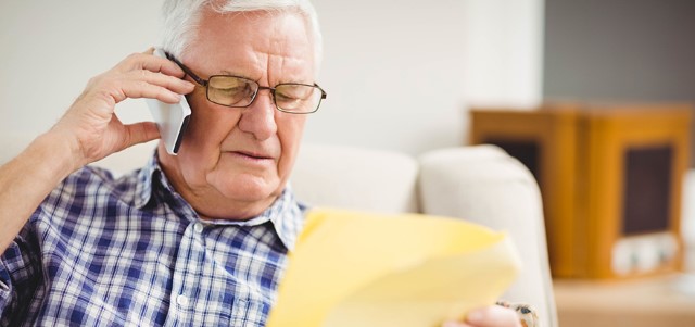 Senior man talking on mobile phone while looking at document