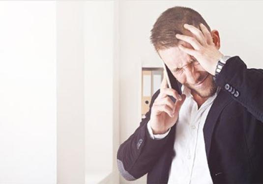 Distressed man on phone holding his head