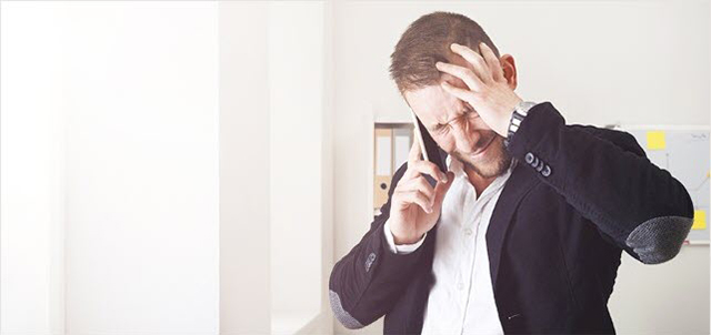 Distressed man on phone holding his head