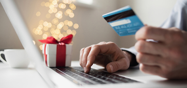 image of man using laptop and holding credit card